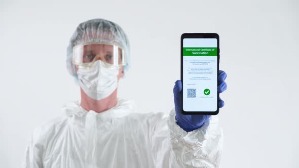 Doctor in Protective Suit Showing a Certificate of Vaccination on a Mobile Phone.