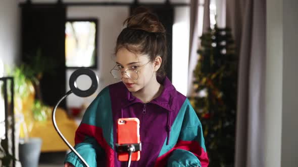 young influencer girl records video on her phone for social media at home alt