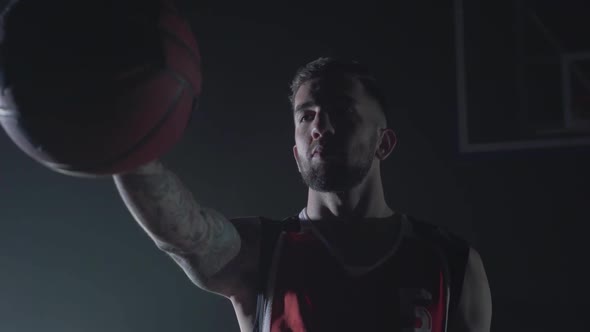 Close Up Portrait Handsome Confident Man in Red Uniform Holding a Ball in Outstretched Hand in the alt