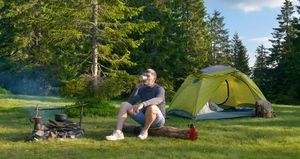 A Bearded Man is Drinking Tea Near the Fire alt