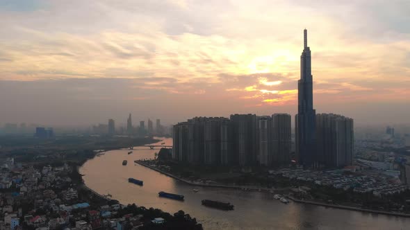 Aerial of boats on Saigon river and distinctive Landmark 81; sunset cityscape alt