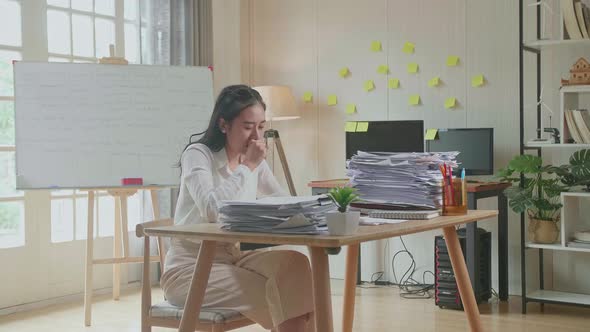 Tired Asian Woman Yawning Before Sleeping While Working Hard With Documents At The Office alt