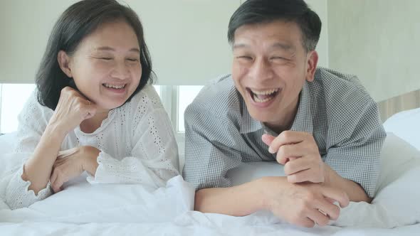 happiness wellness healthy old senior asian couple smile laugh together enjoy laydown casual in bed alt