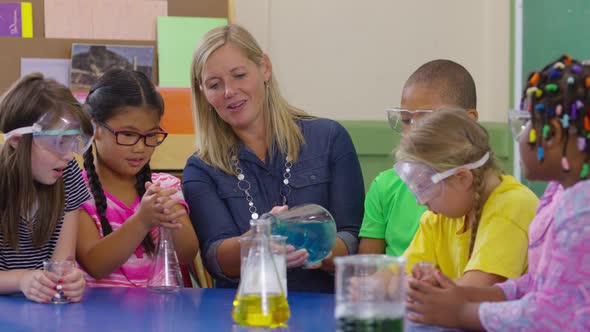 Teacher and students doing science experiment in school classroom alt