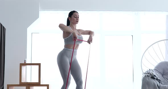 Woman doing exercises with resistance bands at room.