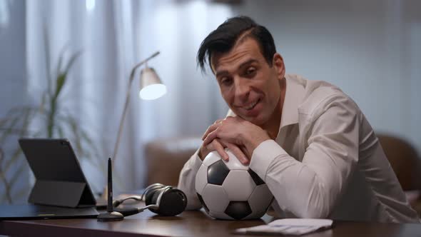 Portrait of Smiling Middle Eastern Man Sitting in Home Office with Face of Sports Ball Looking at alt