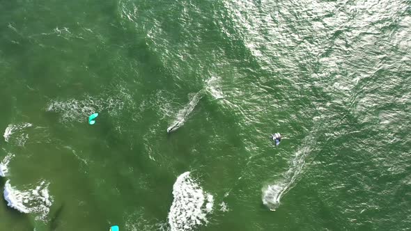 AERIAL: Top View Shot of Surfers Wakeboarding In Summer on a Green Colour Baltic Sea Waves