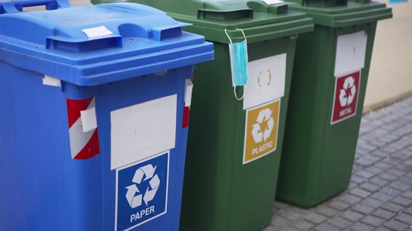 Used Covid19 Face Mask Hanging on Plastic Container for Separate Waste Collection alt