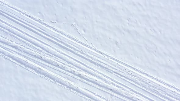 Descending on snowed path with tire trails 4K aerial footage alt