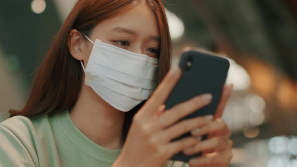 Asian woman wearing medical mask using a smartphone browsing the internet,