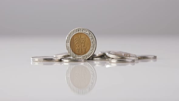 New Israeli Shekels coins rotating on a reflective surface