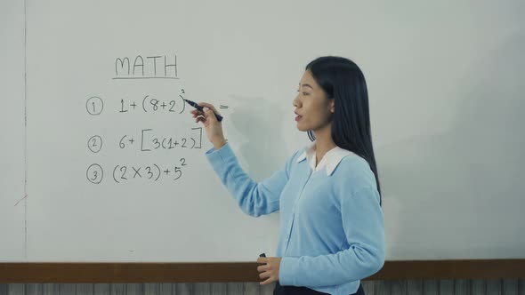 Asian female teacher teaching students at the classroom.