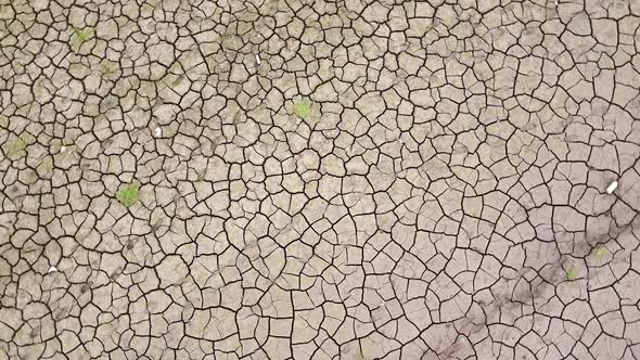 Close-up aerial view of the patterned cracked mud surface of a dry dam due to drought