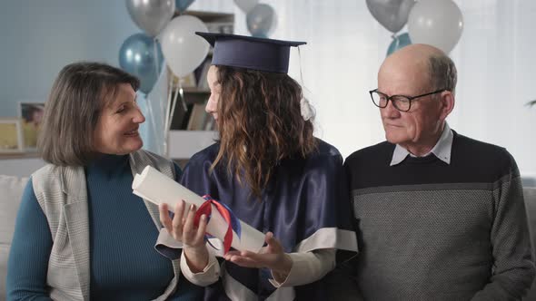 Portrait Happy Family with Graduate Daughter in an Academic Cap and Gown with Diploma in Hands alt