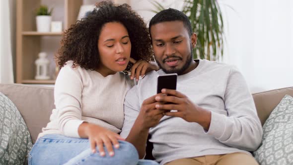 African American Couple with Smartphone at Home alt