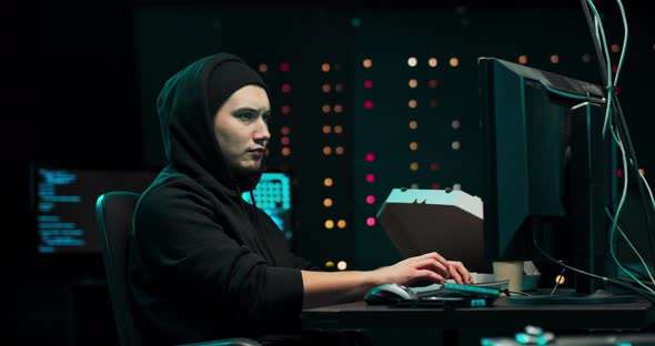 Portrait of Hacker Wearing a Hoodie Tries to Hack a Security System to Steal or alt
