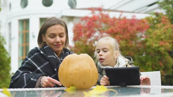 Mother Carving Pumpkin While Daughter Looking for Tips in Internet, Blogging alt