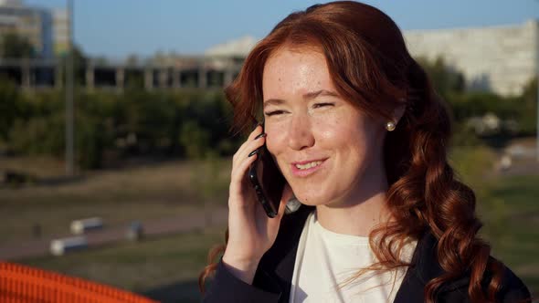 Young Woman with Flecks on Face Talks on Phone Above Street alt