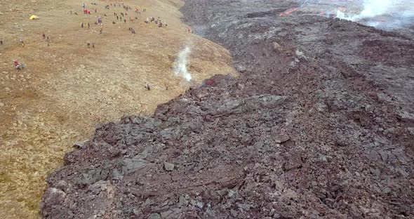 Drone shot of cooling lava with people close by watching the volcano. Fagradalsfjall in Reykjavík, I alt