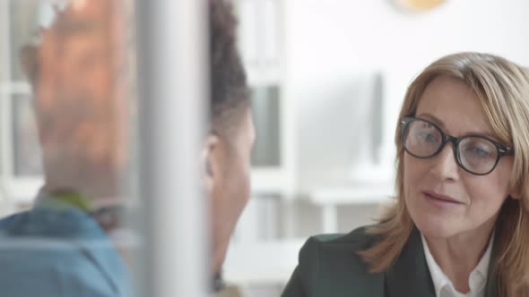 Attentive HR Female Manager Listening to Afro-American Employee in Office alt