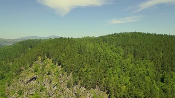 Aerial: Flying Over a Stone Mountain, with Mixed Forest alt