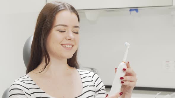 Beautiful Woman Examining Electric Toothbrush