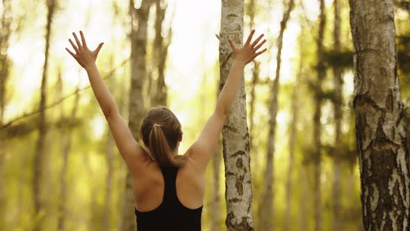 Young Athlete Woman Outstretching Hands Jumping in Nature. Exercise in the Forest, a Healthy alt