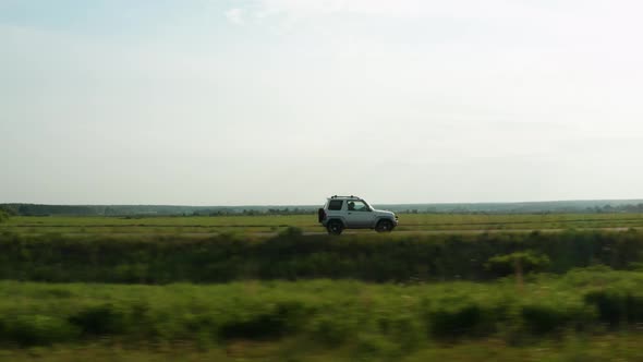 Aerial View of a Car Driving on a Country Road alt