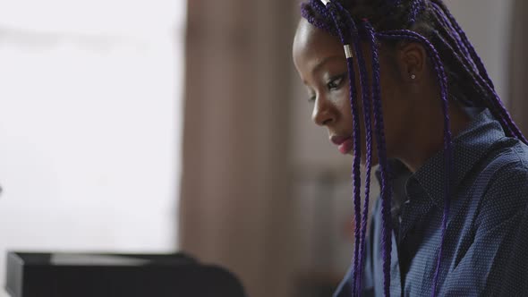 Adult Afroamerican Woman with Purple Dreadlocks is Working with Laptop in Home Office Remote Job at alt
