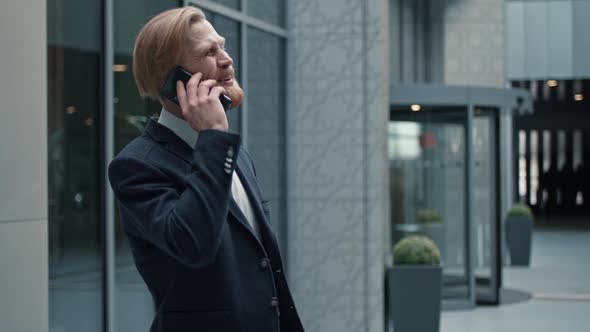 Portrait of Smiling Businessman Answering Phone Call on the Way Out of the Trendy Business Center