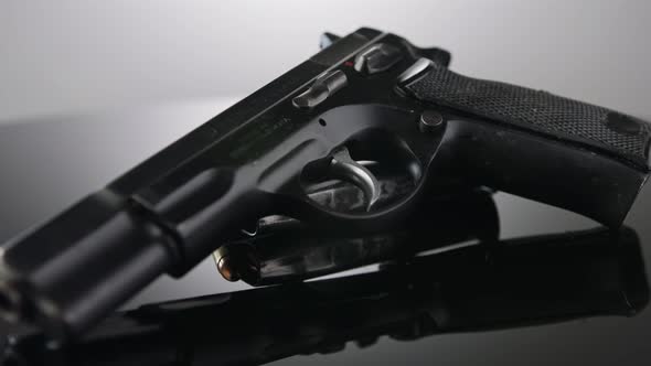 Gun Control. 9mm handgun with bullets rotating on a reflective surface