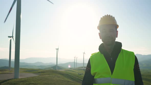 Technician Engineer in Wind Turbine Power Generator Station Standing in Front of the Camera and