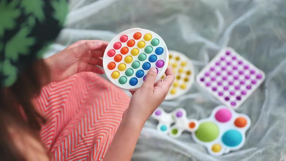 Teen Girl Plays with Antistress Toys Popit and Simple Dimple in the Park on a Summer Day alt