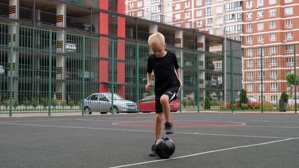 A Boy is Practicing His Ball Skills on a Football Field with a Rubber Coating alt