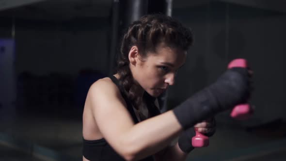 Young Woman Training with Her Hands Wrapped in Boxing Tapes Holding Dumbbells alt
