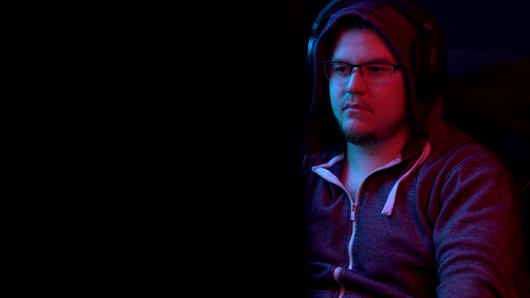 A Young Man Sits at a Computer and Gets Scared. The Man in the Hood Looks at the Monitor and alt