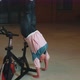 Athletic Girl Make Acrobatic Trick on Bike Exercising Workout on Stationary Cycling Machine Indoors - VideoHive Item for Sale