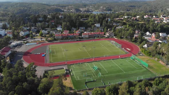 Sports-complex surrounded by lush green nature in countryside; drone view alt