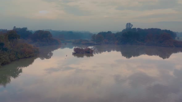 Landscape with lake view and a single road bordering it at misty autumn morning in Central Europe. A alt