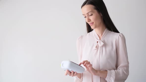 Young Brunette Girl on a White Background She Works with a Mobile Printer alt