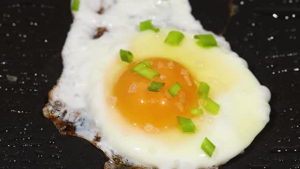 Sprinkling green scallion on sunny side up eggs alt