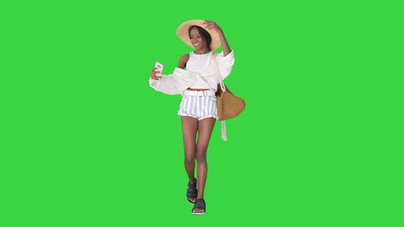Smiling African American Woman in a Straw Hat Taking Selfie While Walking on a Green Screen Chroma alt