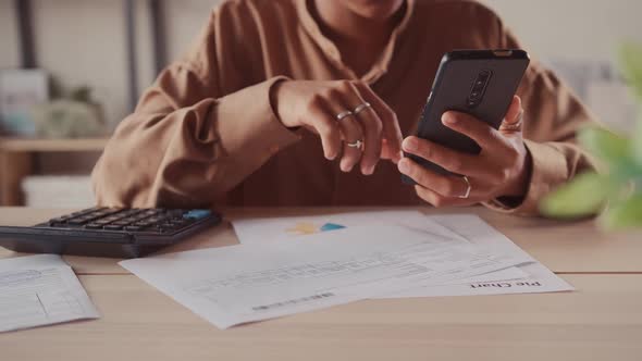 African Accountant Makes Calculations on Calculator Use App on Smart Phone alt