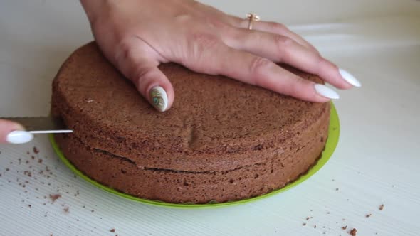 The Woman Cuts The Biscuit Cake. For Chocolate Cake With Peanuts alt