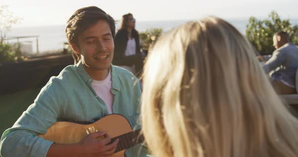 Young man playing guitar on a rooftop with his friends alt