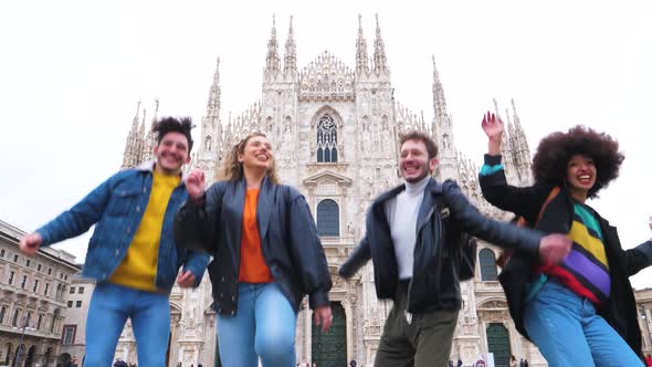 Group of for multiethnic people friends jumping in front of milan cathedral alt