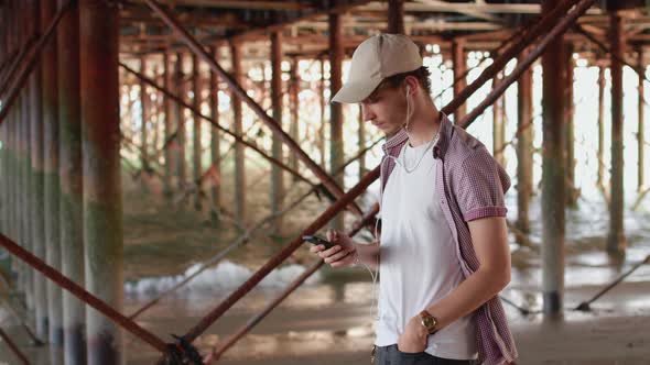 Man Listening To Music on Headphones Under Pier alt