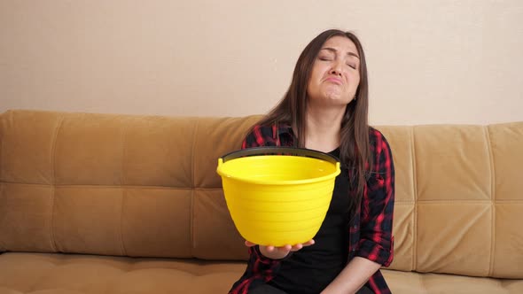 Sad Woman Collects Water Flowing Down From Ceiling on Sofa alt