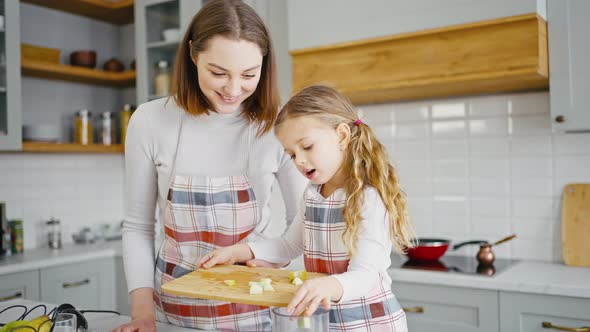 Little Girl Learning to Cook with Mother Preparing Healthy Smoothie at Kitchen Adding Fruit to alt