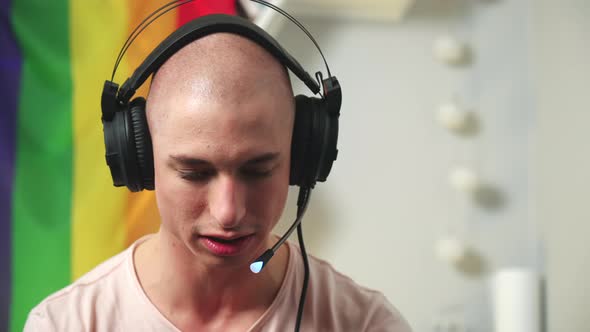 Close Up Portrait of a Bald Queer Gamer Playing Video Games While Using Professional Headset alt